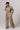 Person wearing a beige jumpsuit on a plain background